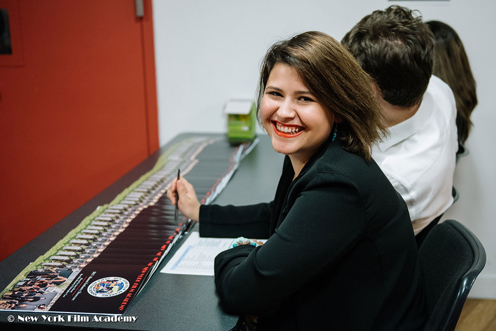 NYFA LA Alumni Industry Showcase woman smiling at student information table.