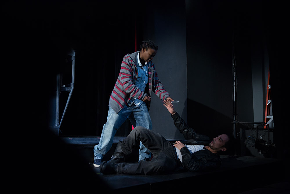 NYFA And Then They Fell actor holding knife towards actor on the floor of the stage.