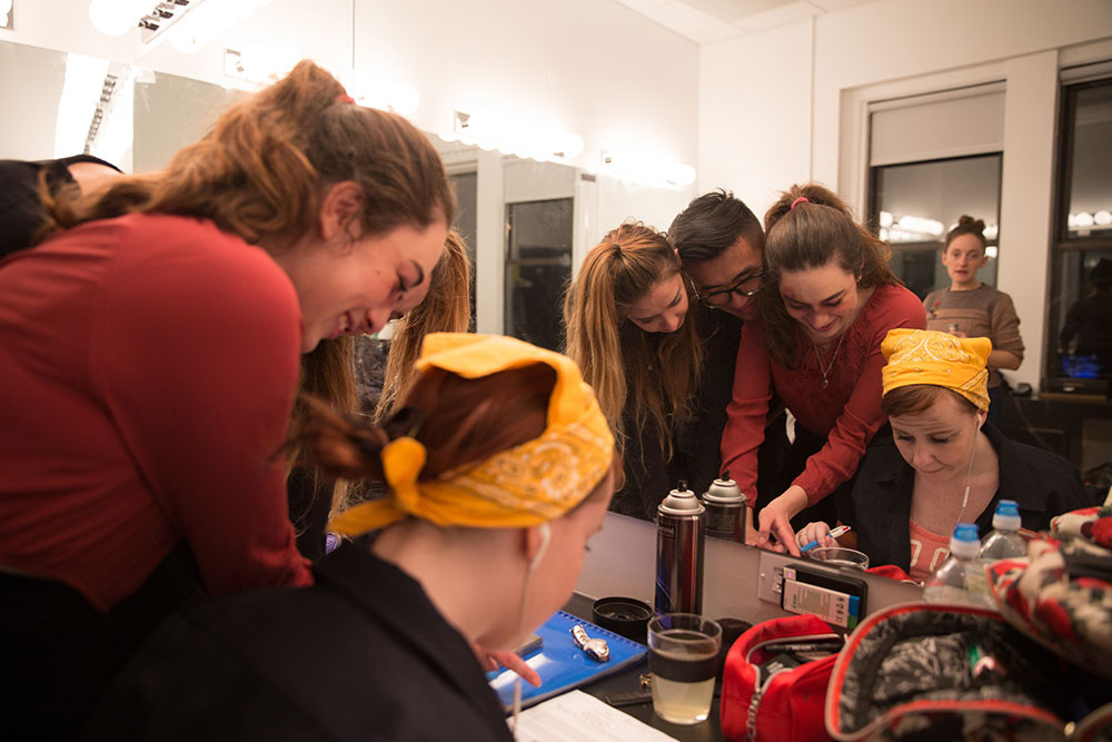 NYFA And Then They Fell students practicing makeup in front of mirror.