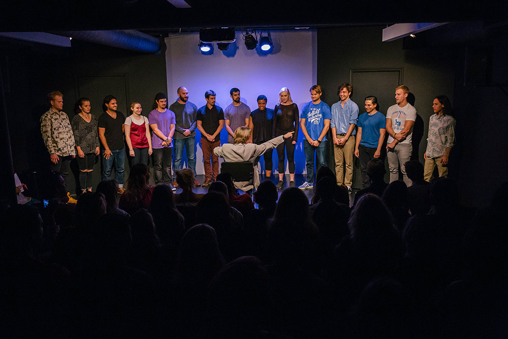 NYFA LA play man directing on stage with student actors in front of a crowd.