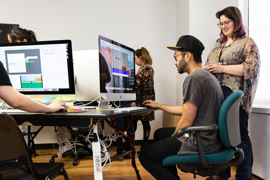 Woman watching man play a computer game