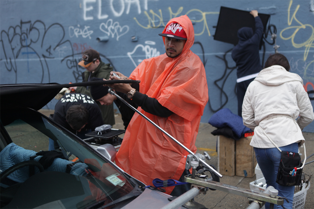 Crew member setting up car camera rig structure