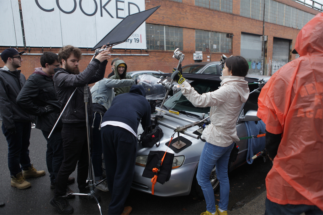 Crew members setting up car camera rig and adjusting lighting