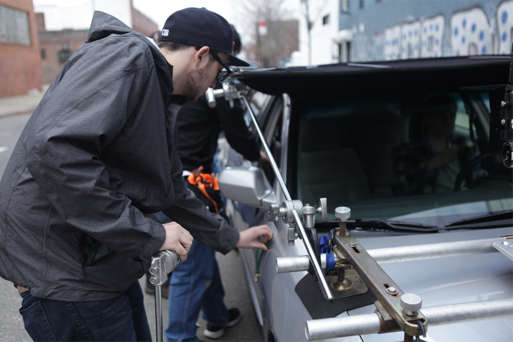 Crew member setting up car camera rig