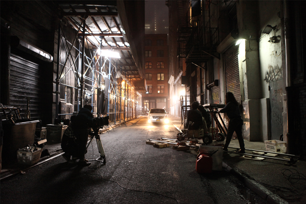 People filming a car in an alley at night