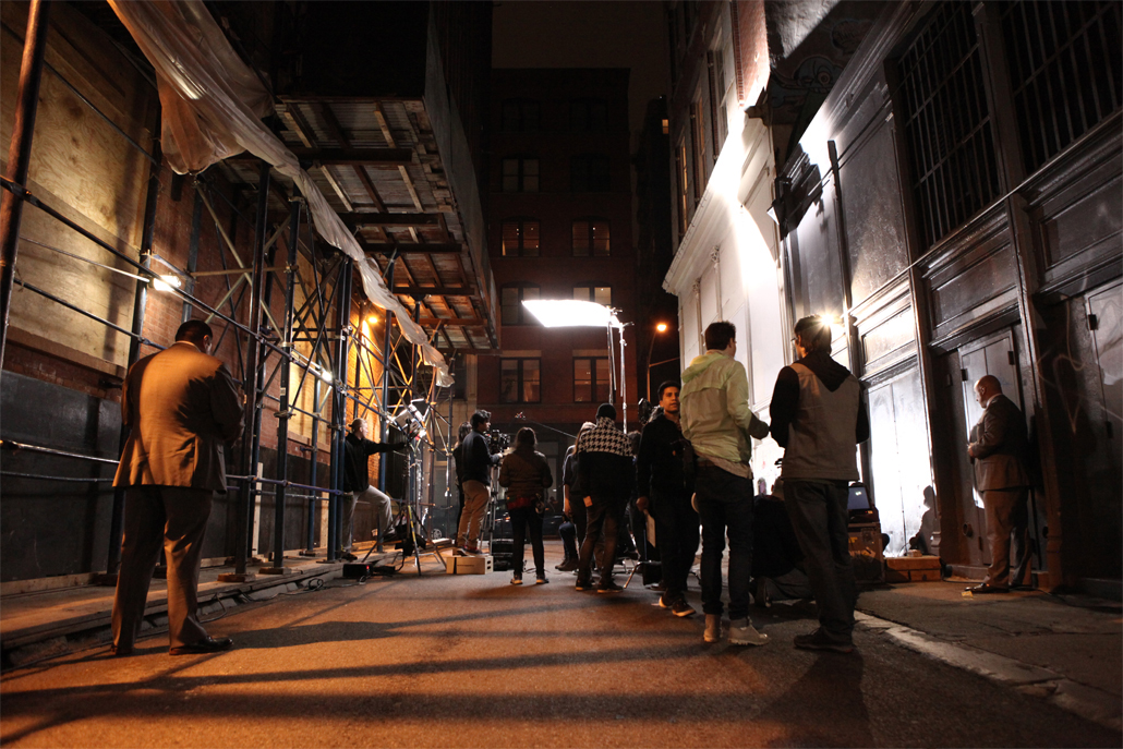 Several people in an alley filming at night