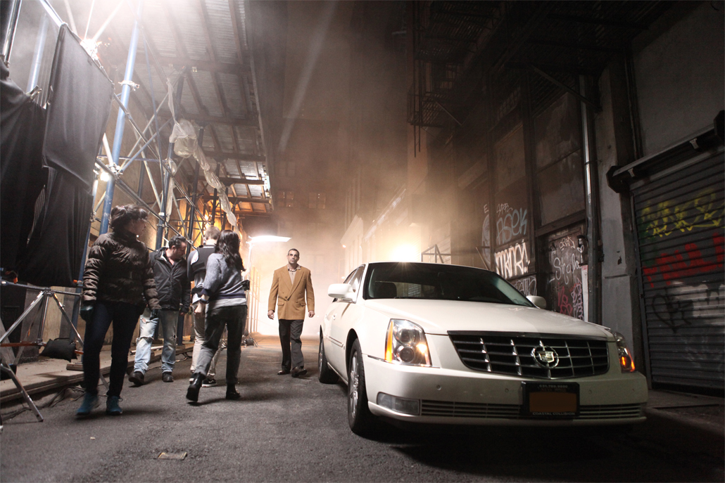 A white cadillac car in an alley with people around it