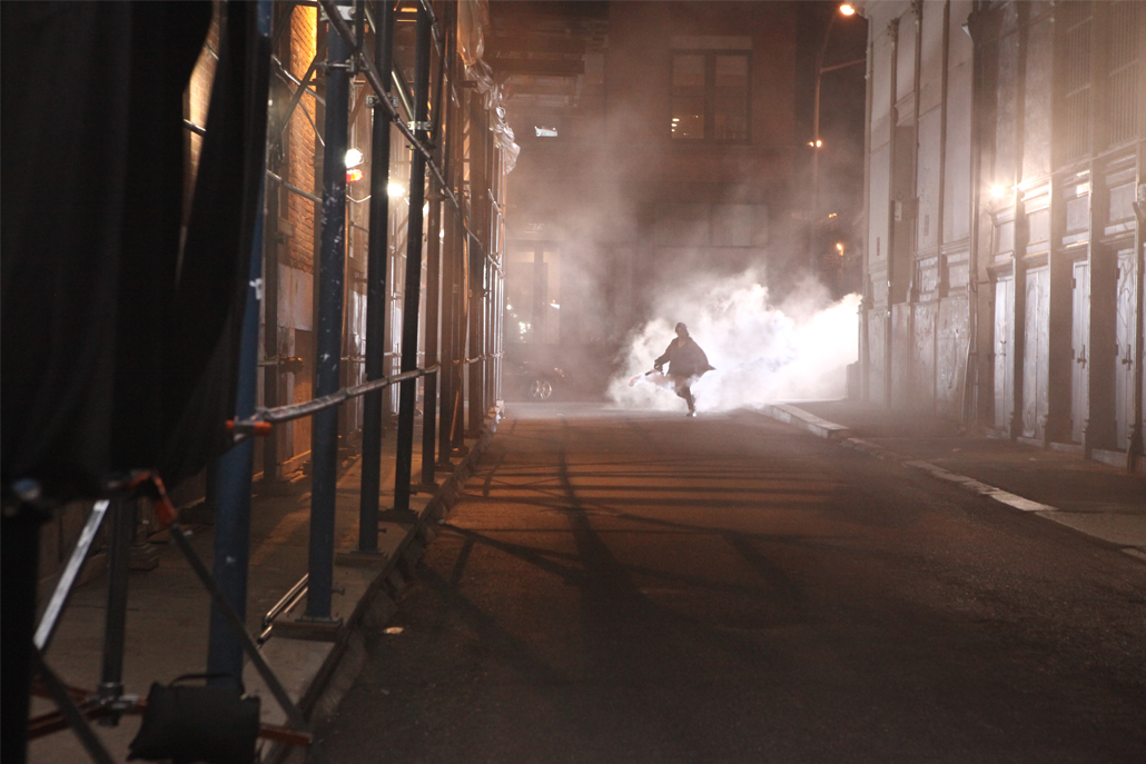 Crew member using fog machine and running down an alley