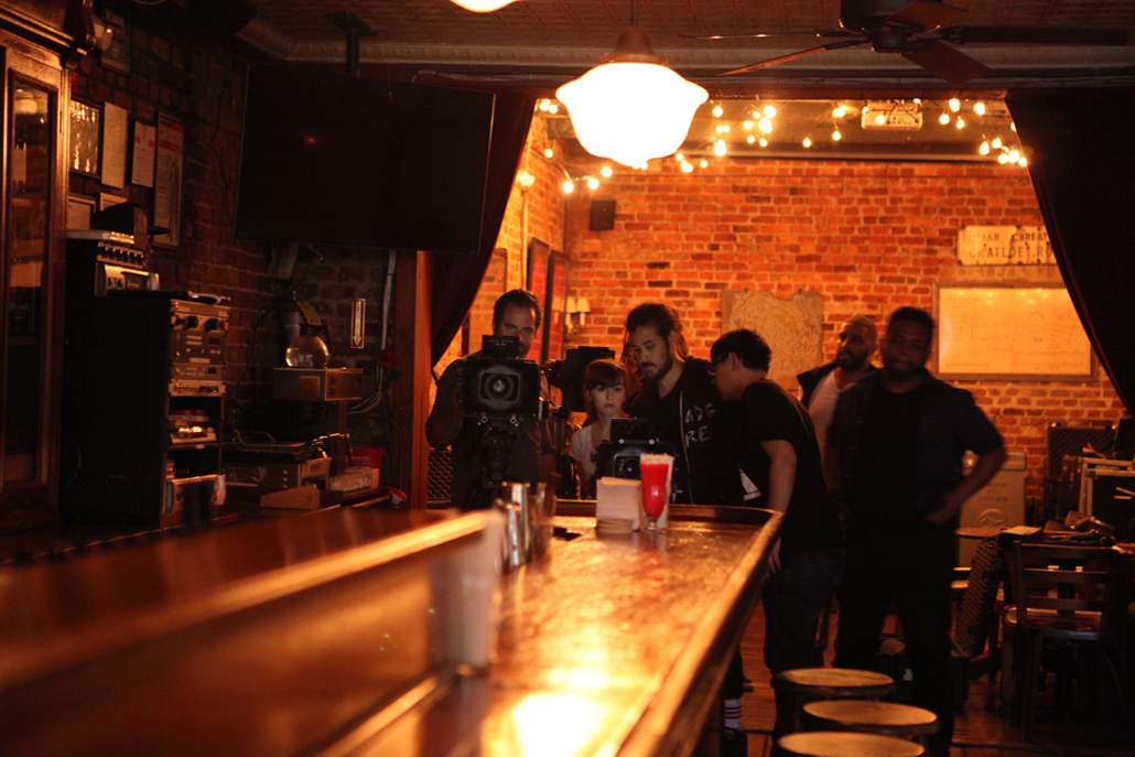 People in a bar gathered around a camera