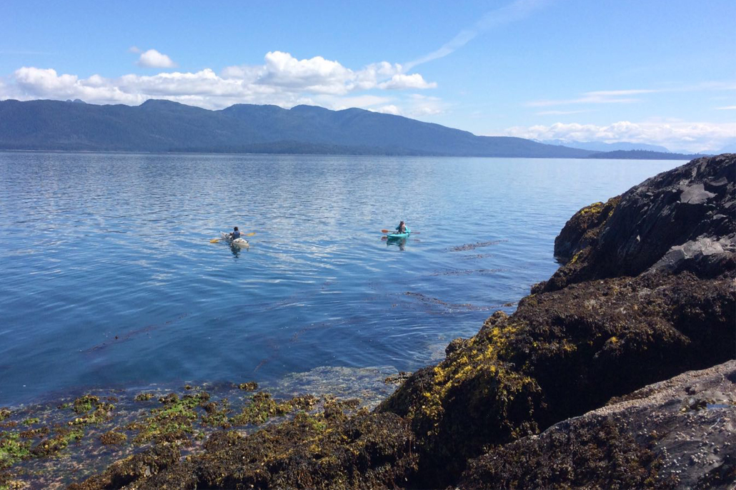 ﻿Ocean and mountain landscape with two people canoeing