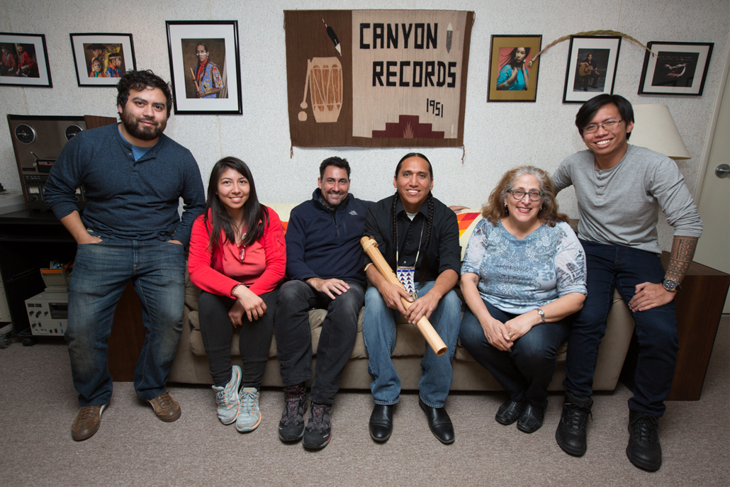 Group of people sitting on could in front of Native American photos