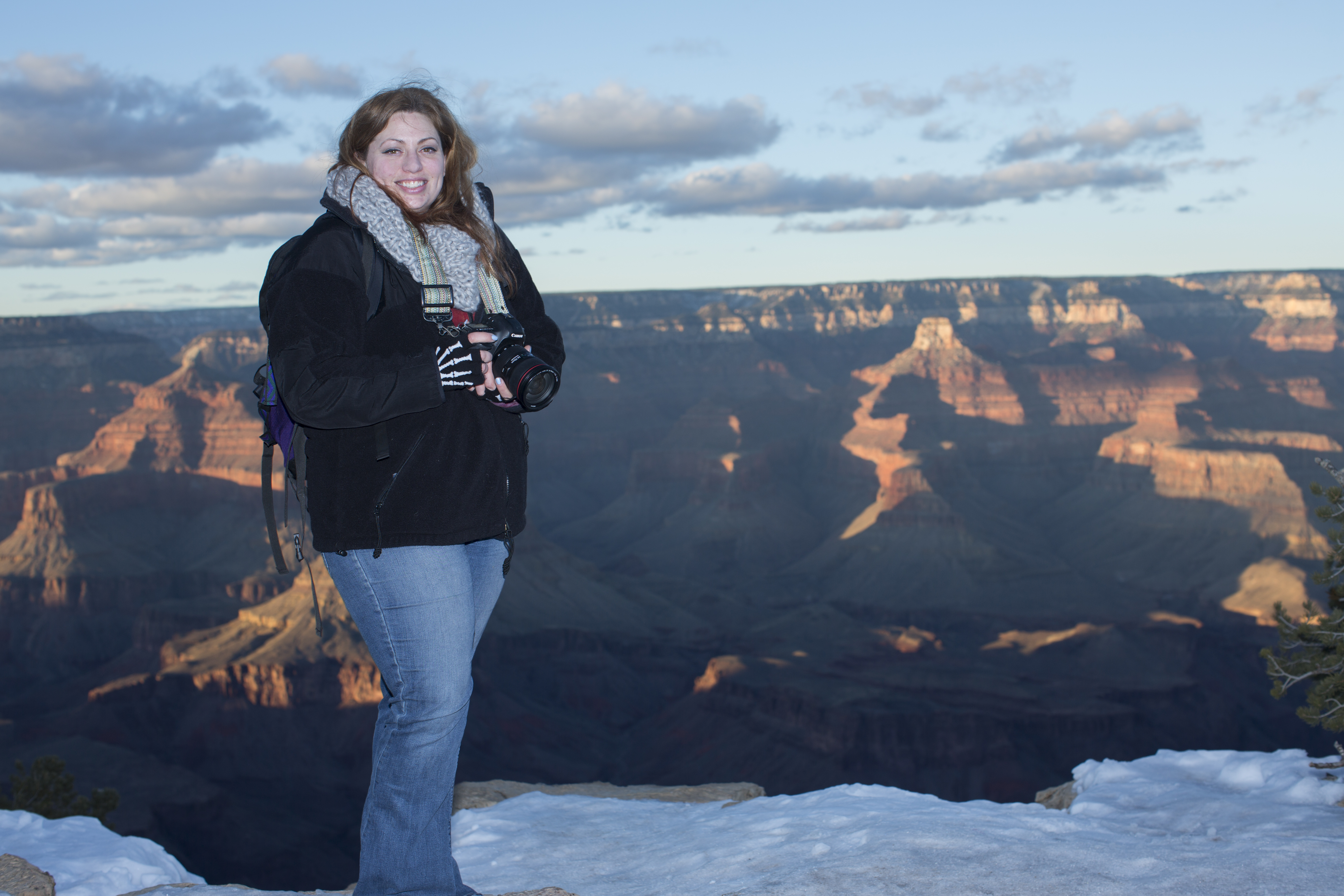 Woman holding camera smiling in front of canyon