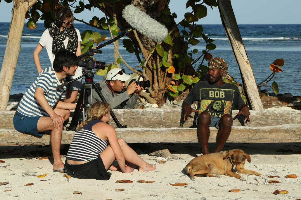 Film crew interviewing man on beach with dog