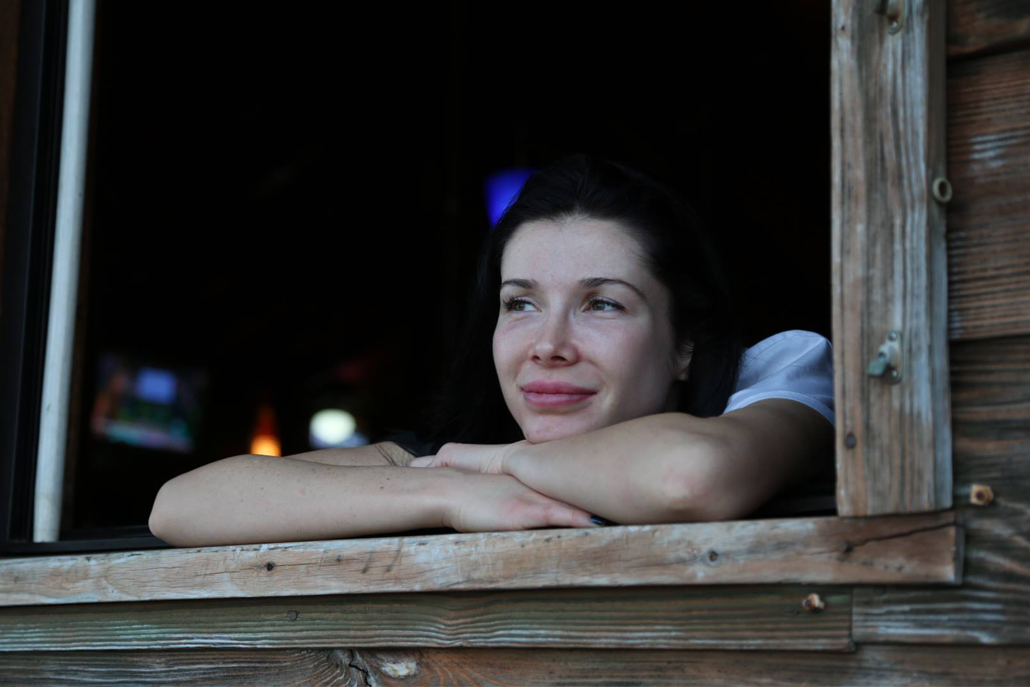 Woman smiling out of wooden window pane