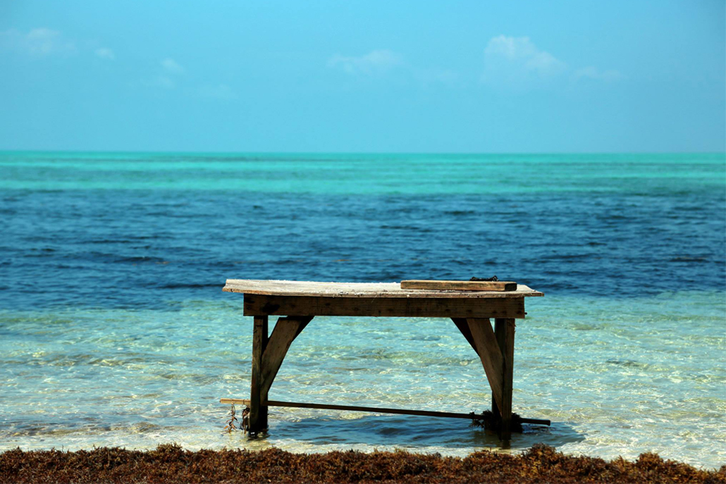 Wooden table sitting in shallow part of ocean shore