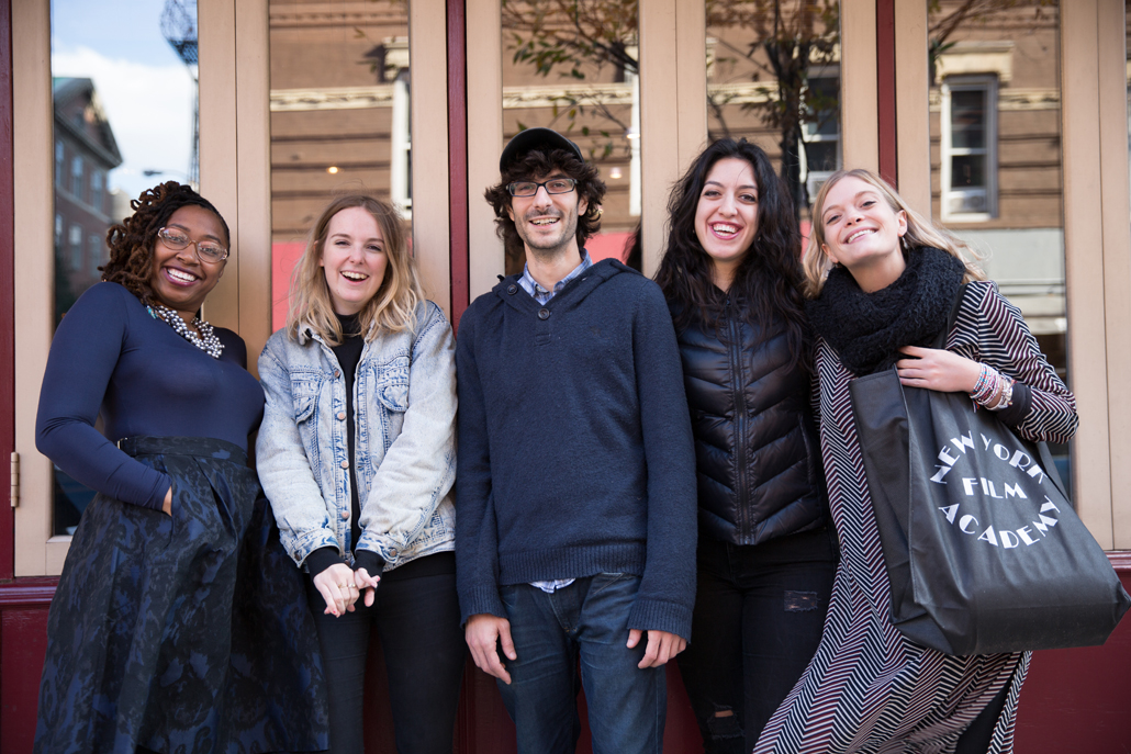 Group of people smiling in front of windows of building