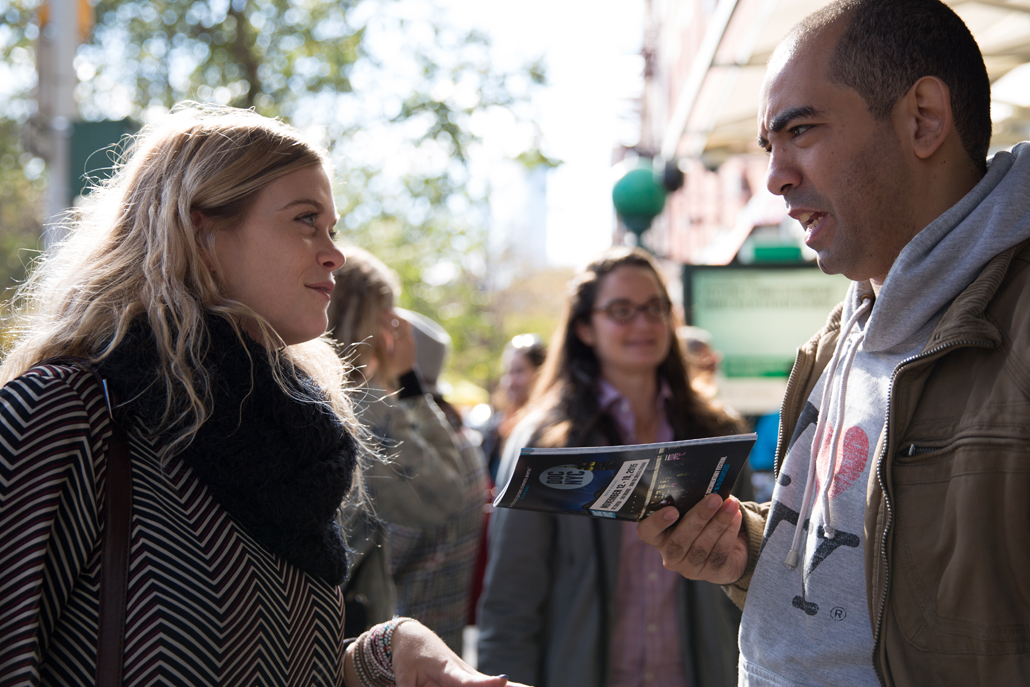 Man speaking to woman with pamplet in hand