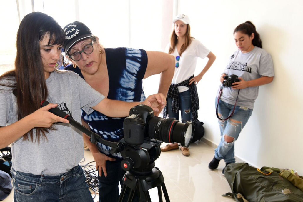 Women looking into camera lens with women standing behind them