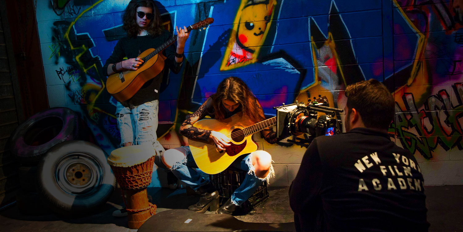 man filming actors playing guitar