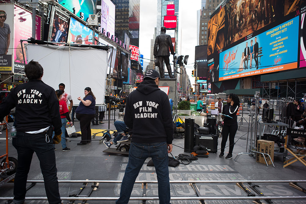two students in new york film academy jackets on set in times square