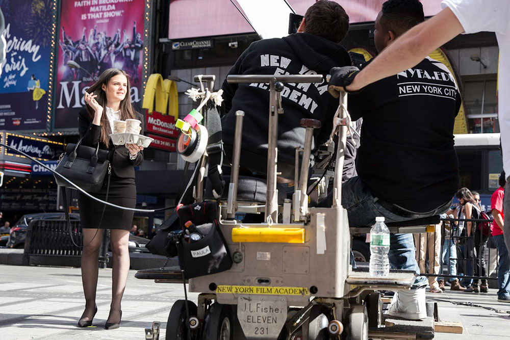 students watching girl on set in times square