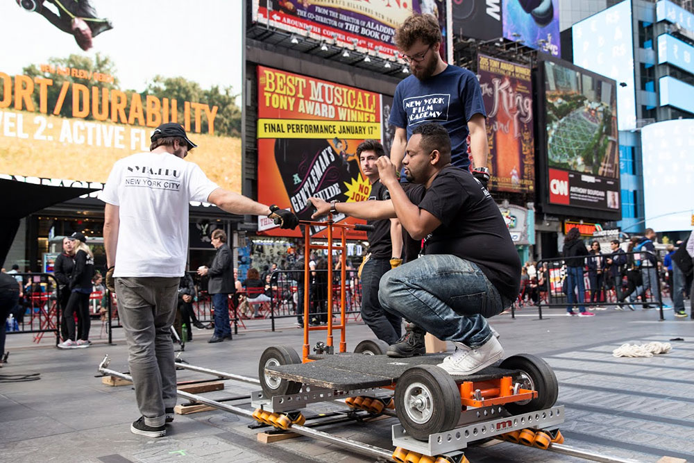 man sitting on camera dolly directing on a film set