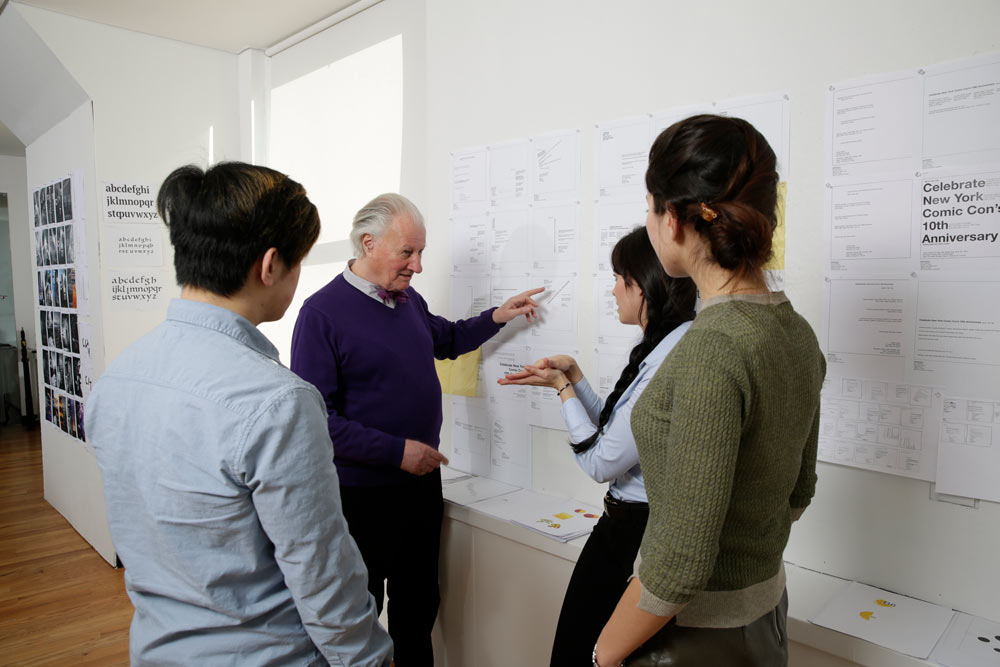 3 students and a professor discussing something on the board