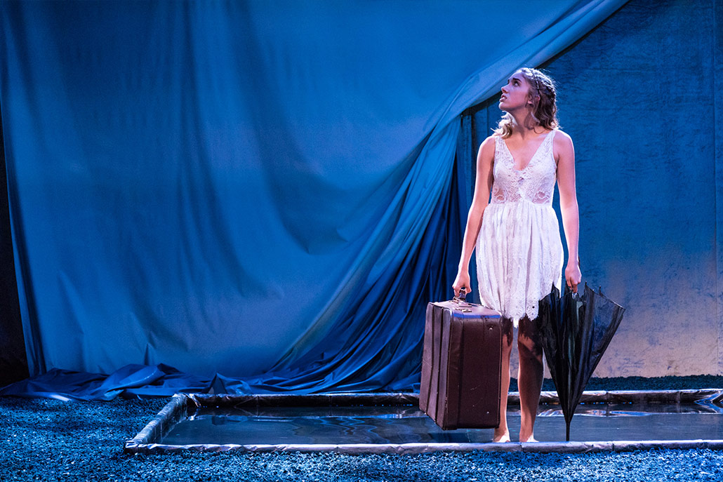 NYFA musical theater student holding suitcase and umbrella performing Eurydice.