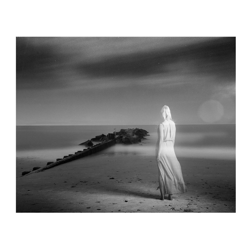 Transparent woman standing on shoreline of foggy island