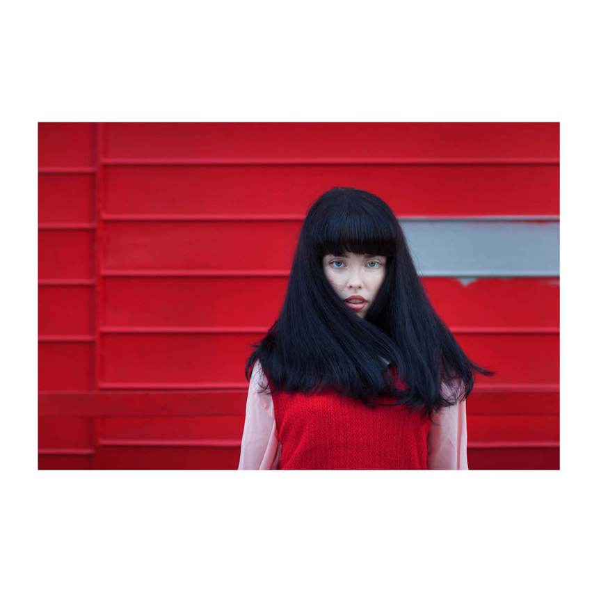 Woman in red sweater posing in front of red background