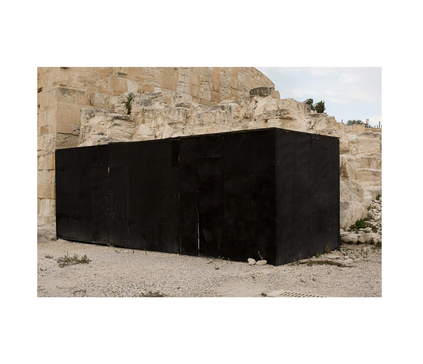 Large black rectangular box sitting in front of rocky hills