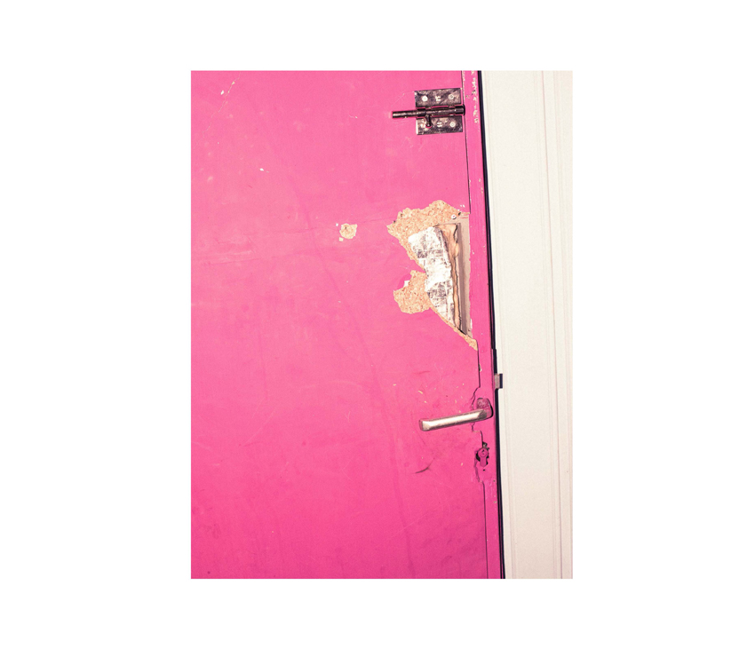 Worn down pink door with white wall