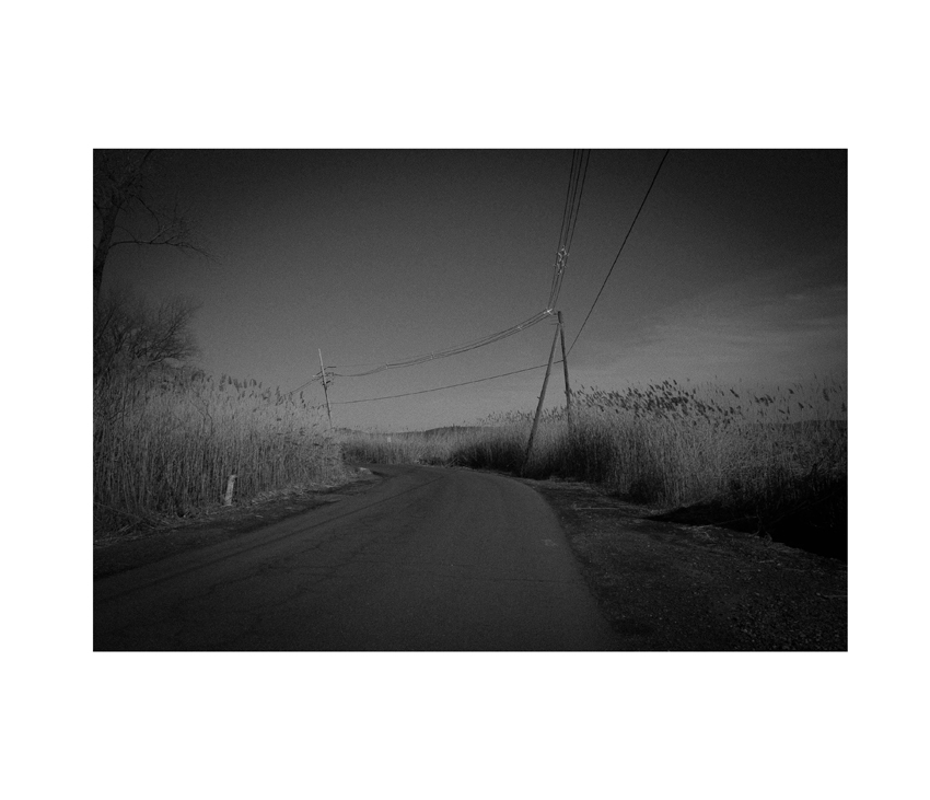 Black and white photo of rural road with telephone poles