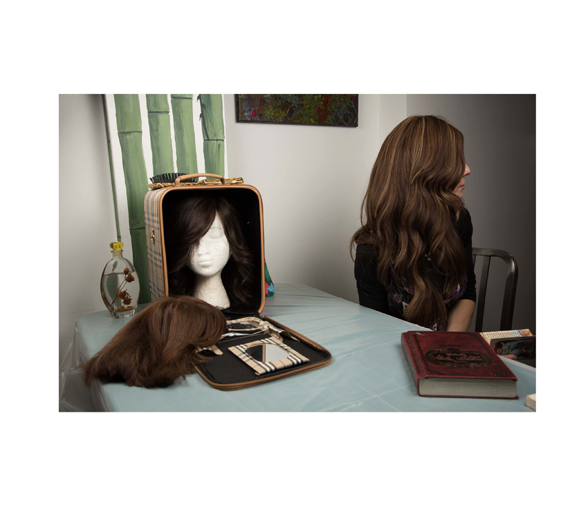 Woman sitting with bag of wigs on top of table