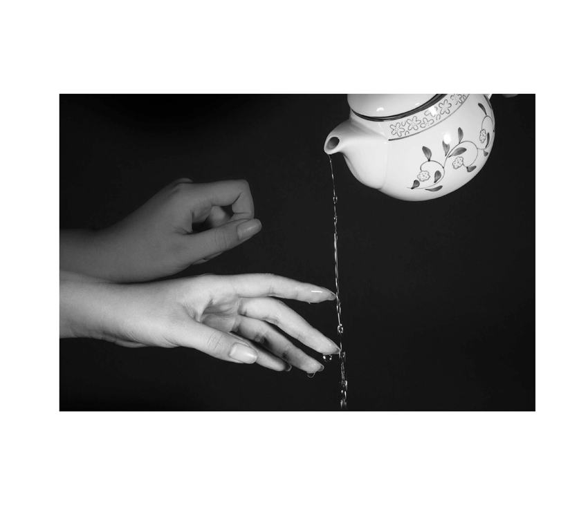 Woman's hands touching water pouring out of tea cup