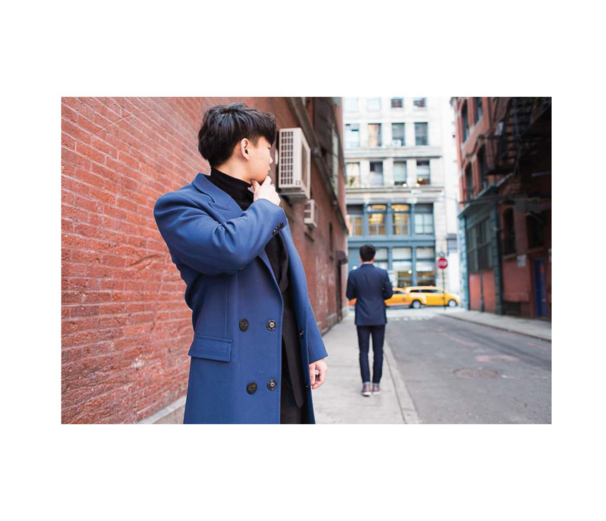 Man looking behind him on city street wearing blue coat