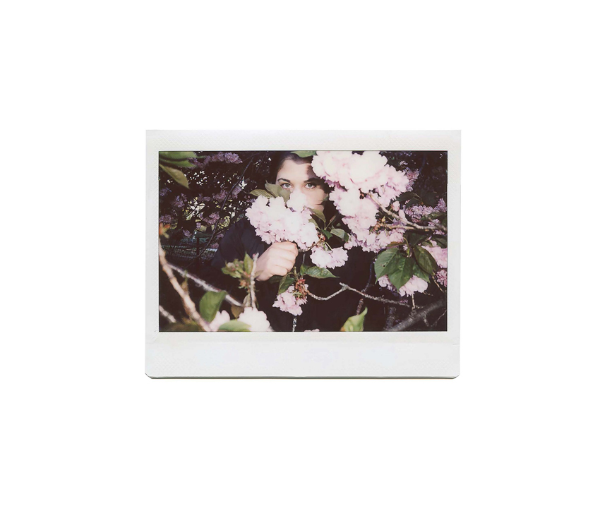 Woman posing between pale pink flower tree