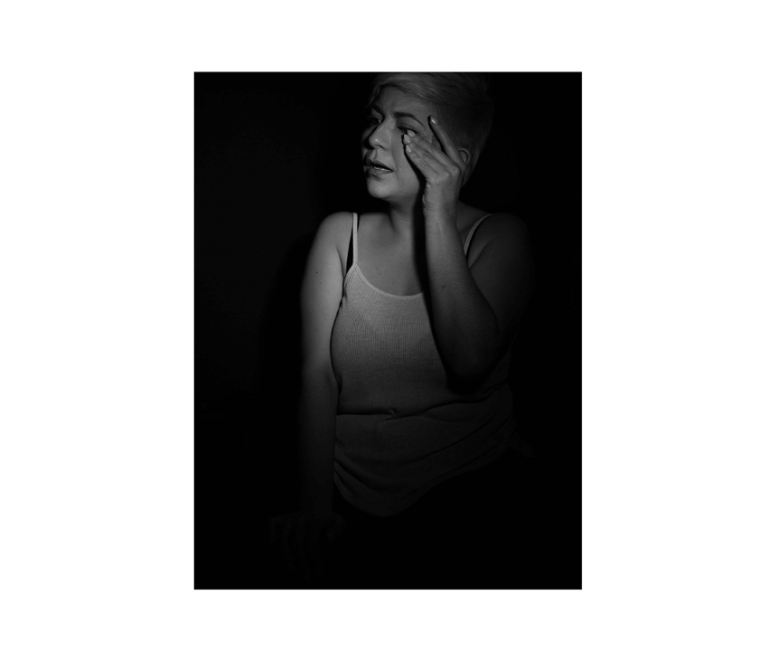 Girl wiping face while crying in front of black background