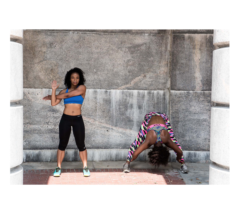 Two women in workout clothes climbing fence
