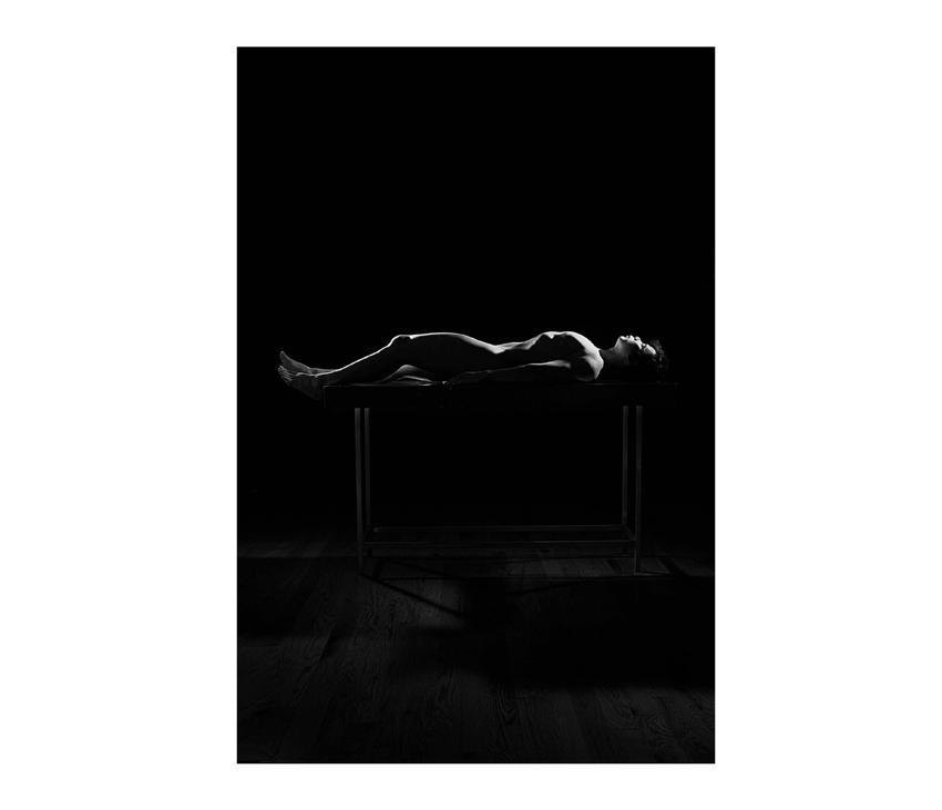 Black and white photo of naked body laying on table