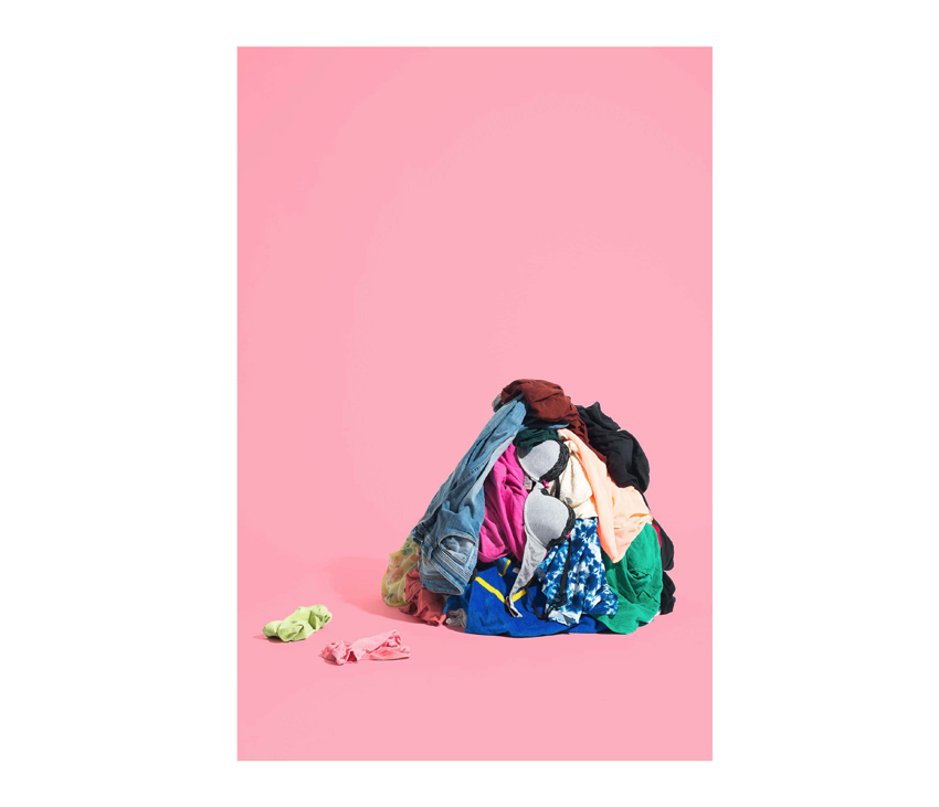 Pile of clothes laying in front of pink background