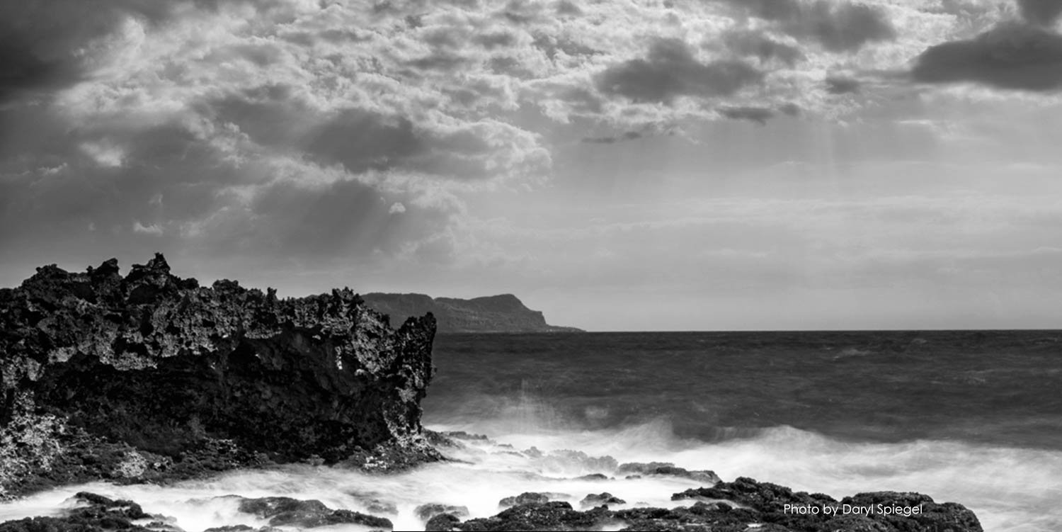 ﻿Black and white photo of ocean with rocky shore
