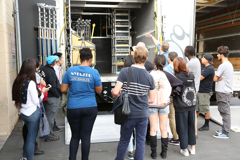 Students from NYFA class learning about film equpiment stored on shelves at Grounded Hollywood.