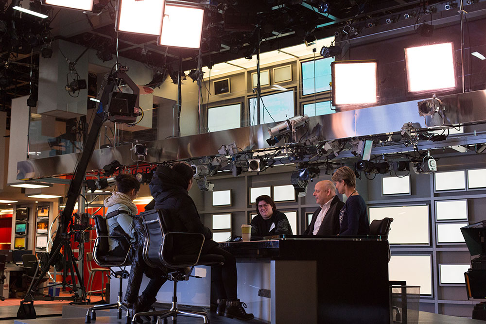 smiling group of nyfa students sitting at MSNBC News desk