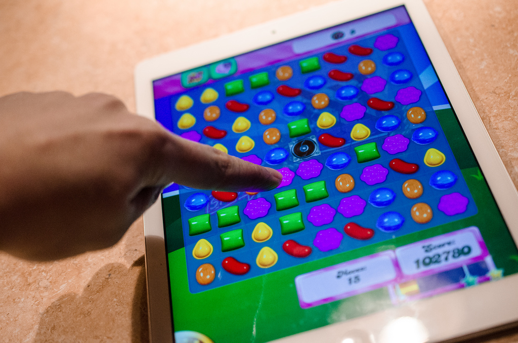 finger playing candy crush on iPad
