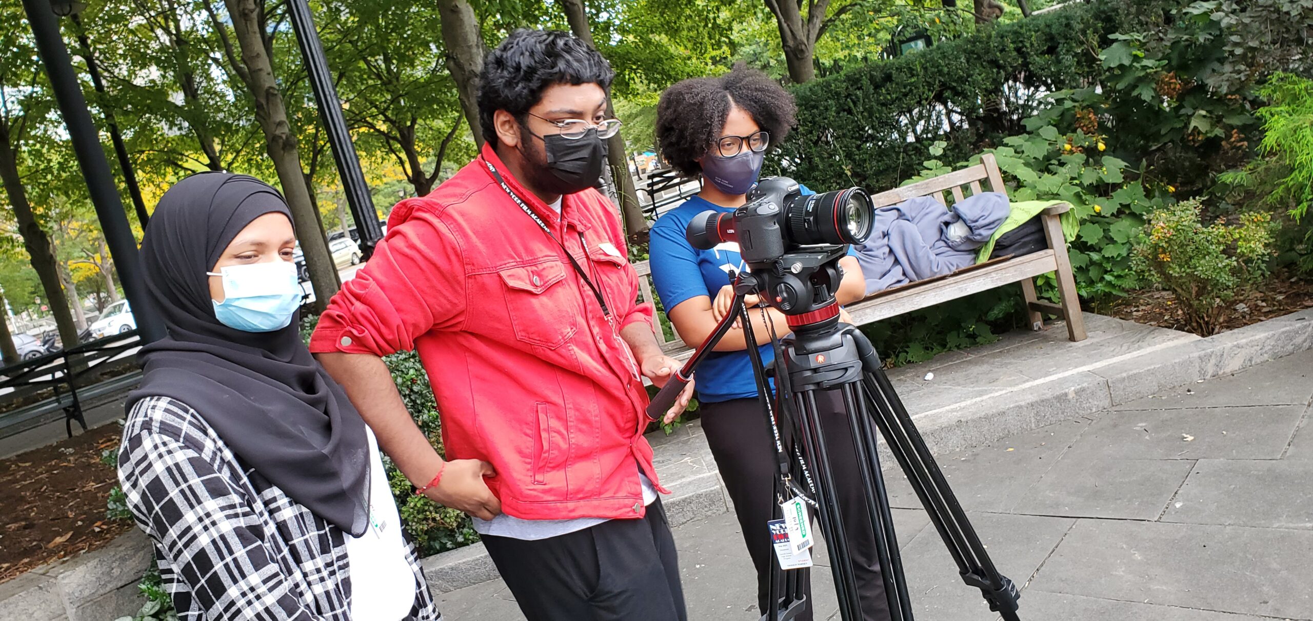 Three DeWitt Clinton High School students stand behind a camera.