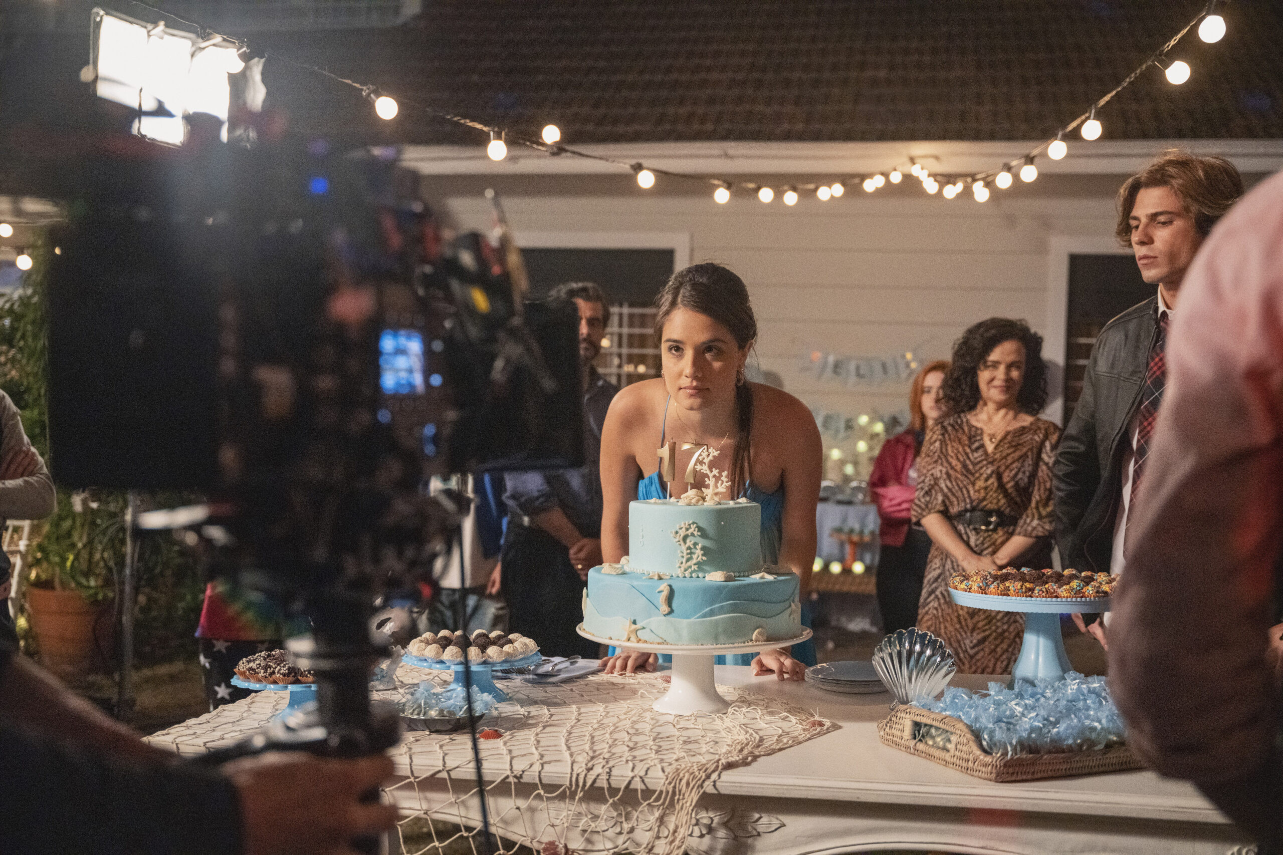 Amanda Azevedo on the set of Back to 15 with a blue cake in front of her.
