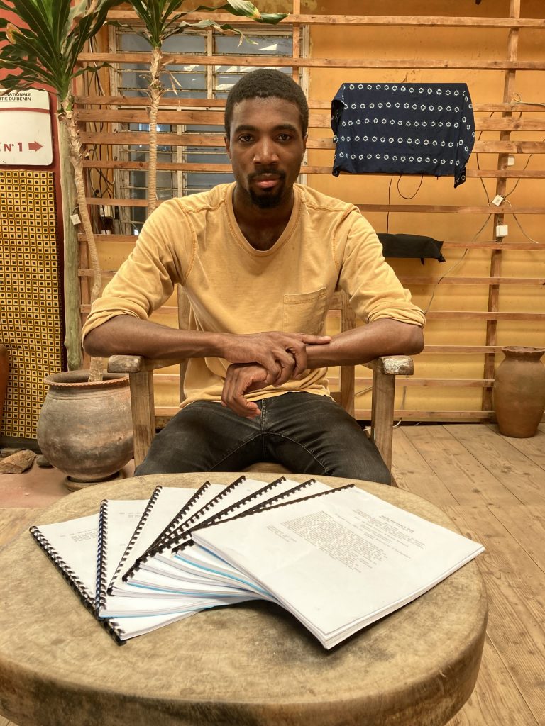 man sitting at a table with a number of scripts fanned out on the table